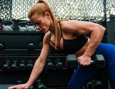 A fit woman lifting weights in a gym setting illustrating determination and strength.